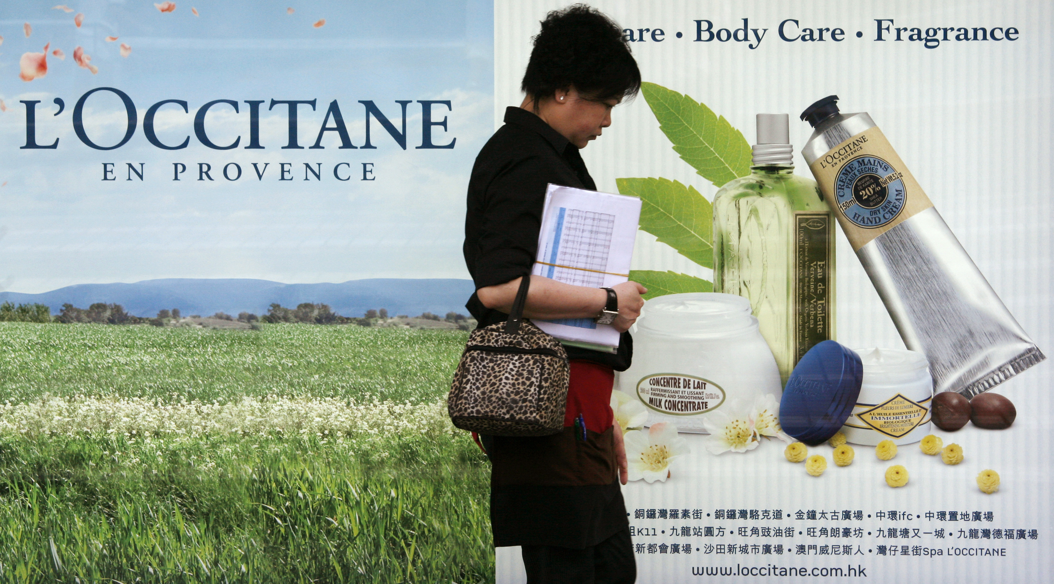 A woman walks past a L'Occitane advertisement in Hong Kong